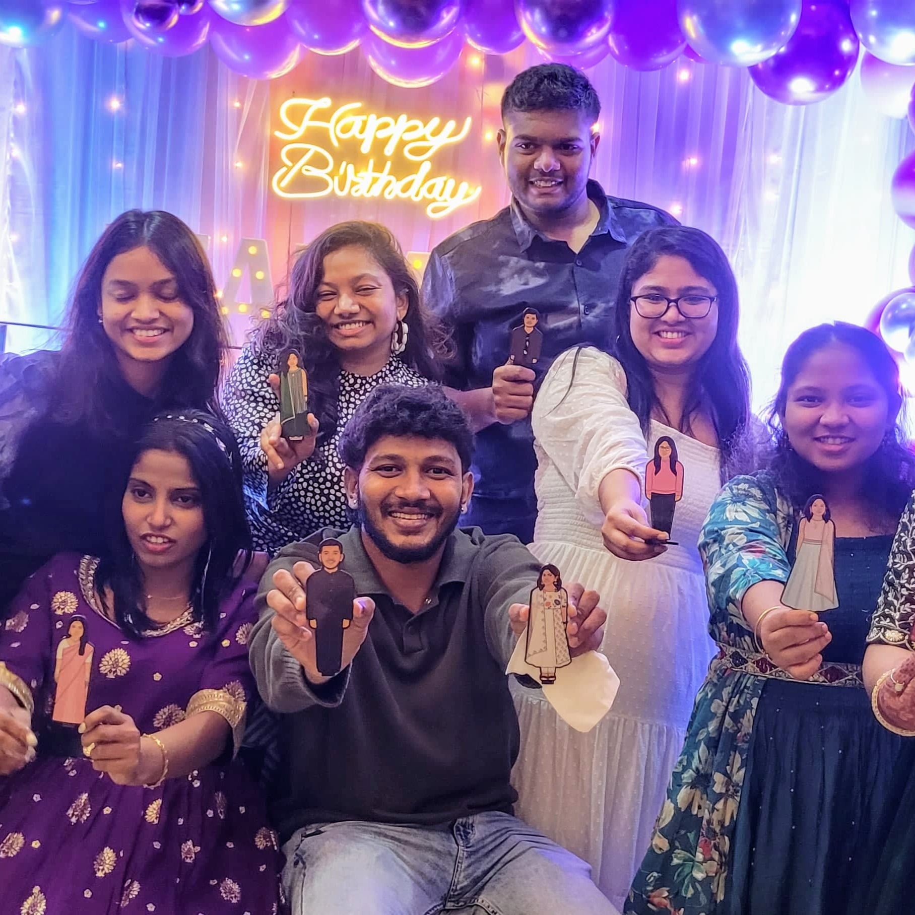 Group of people celebrating a birthday with decorations and balloons.